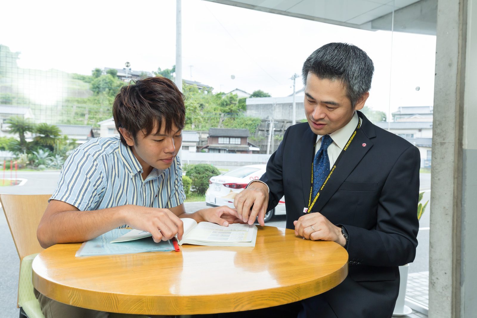 教習生と指導員がテーブルで教本を見ながら話している